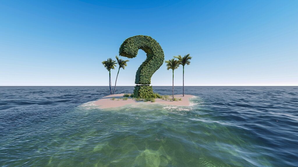 A question mark symbol made carved out from bushes in-between palm tress on a deserted island.