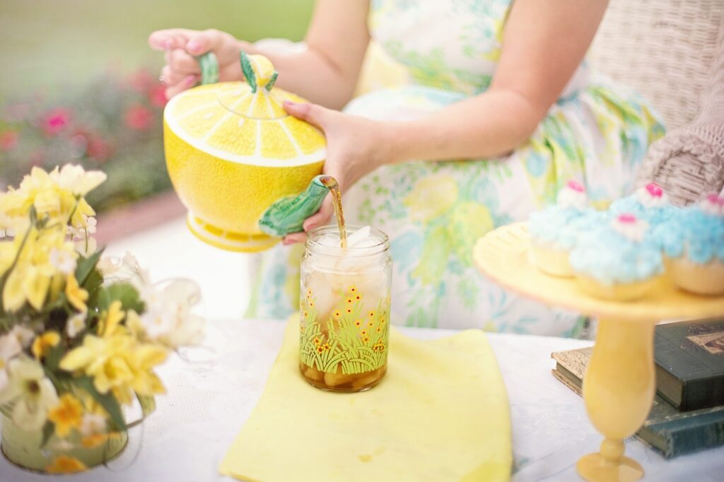 A girl pouring tea from a yellow teacup into a glass.