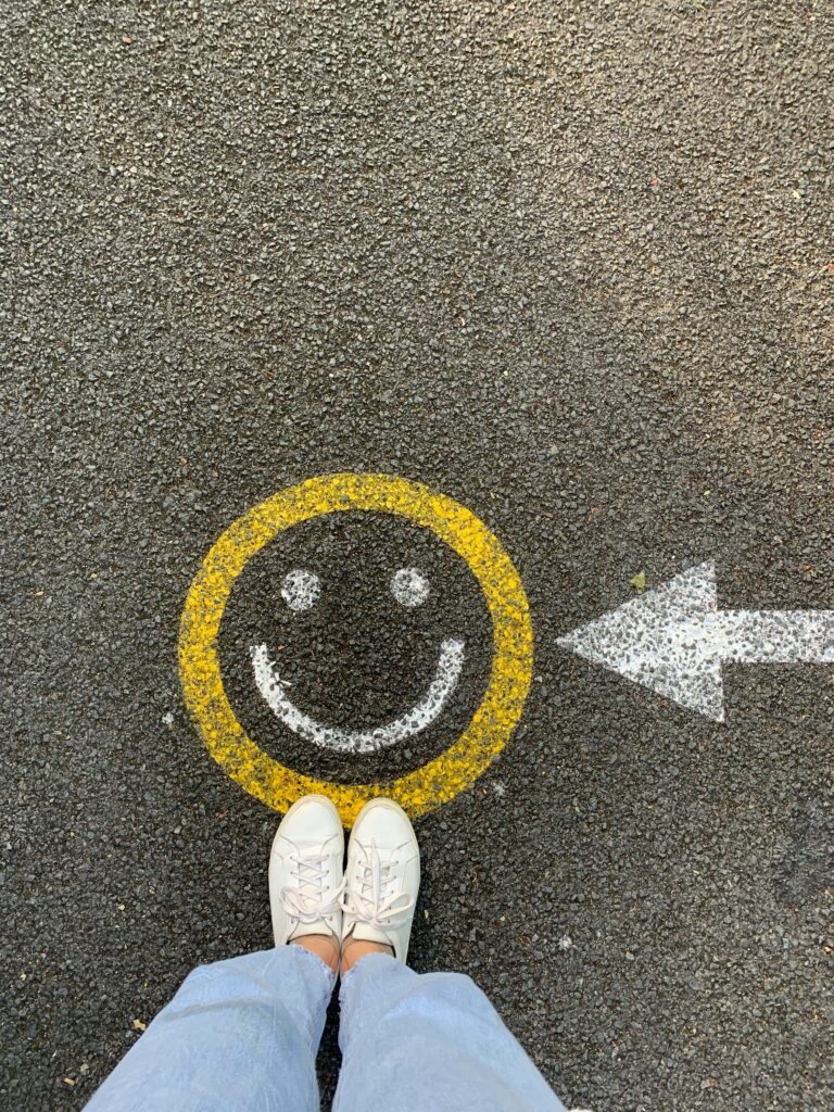 Two shoes standing in front of a smiley face to point you to find your happy place.