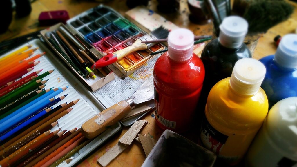 A photo of colorful paint supplies, including colored pencils, water color, and finger paints.